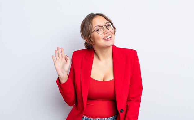 Foto mujer bonita hispana sonriendo alegremente, saludando con la mano, dándote la bienvenida y saludándote. concepto de empresaria