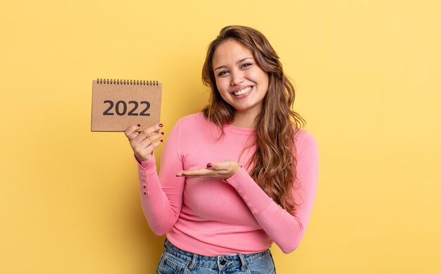 Mujer bonita hispana sonriendo alegremente sintiéndose feliz y mostrando un concepto de calendario concepto