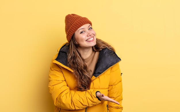 Mujer bonita hispana sonriendo alegremente, sintiéndose feliz y mostrando un concepto. ropa de invierno