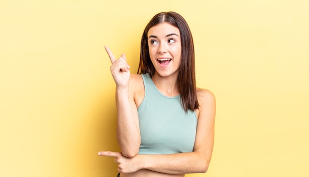 Mujer bonita hispana sonriendo felizmente y mirando hacia los lados, preguntándose, pensando o teniendo una idea