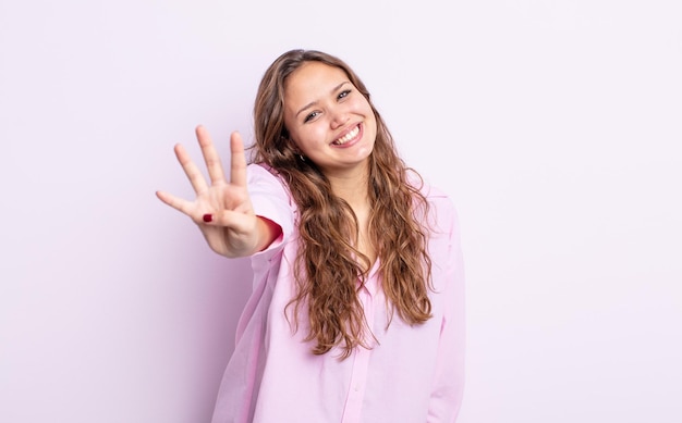 Mujer bonita hispana sonriendo y mirando amistosamente, mostrando el número cuatro o cuarto con la mano hacia adelante, contando hacia atrás