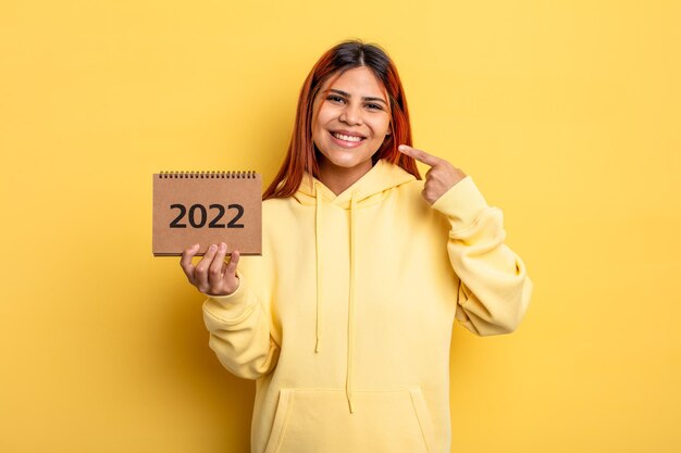 mujer bonita hispana sosteniendo un calendario o agenda 2022