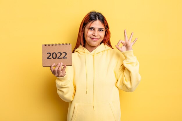 Mujer bonita hispana sosteniendo un calendario o agenda 2022