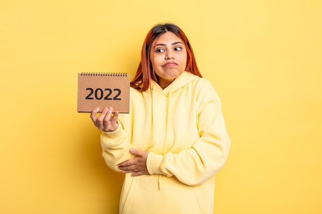 mujer bonita hispana sosteniendo un calendario o agenda 2022