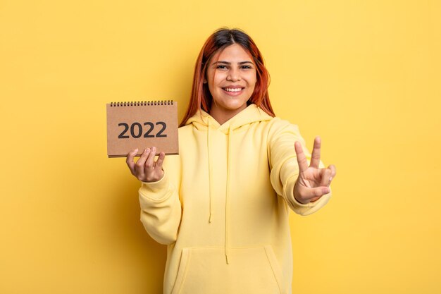 Mujer bonita hispana sosteniendo un calendario o agenda 2022