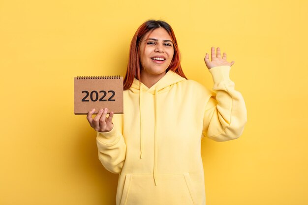 Mujer bonita hispana sosteniendo un calendario o agenda 2022