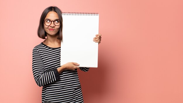 Mujer bonita hispana sosteniendo un cuaderno de bocetos