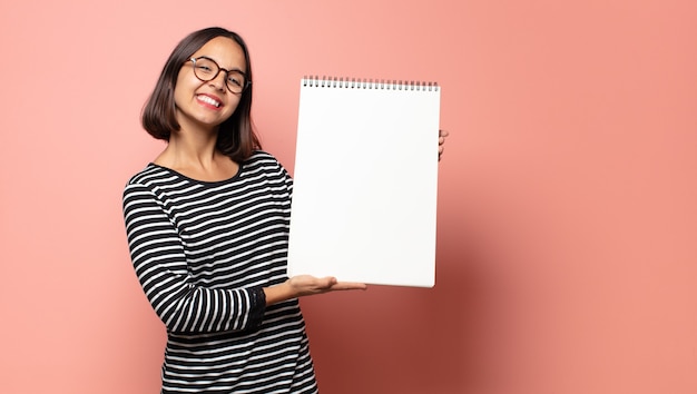 Mujer bonita hispana sosteniendo un cuaderno de bocetos