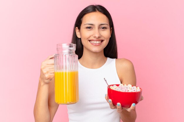 Mujer bonita hispana con un tazón de desayuno con hojuelas y jugo de naranja