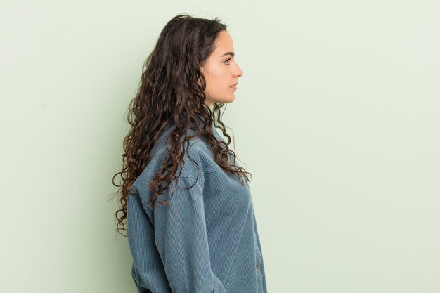 Mujer bonita hispana en la vista de perfil que busca copiar el espacio por delante pensando imaginando o soñando despierto