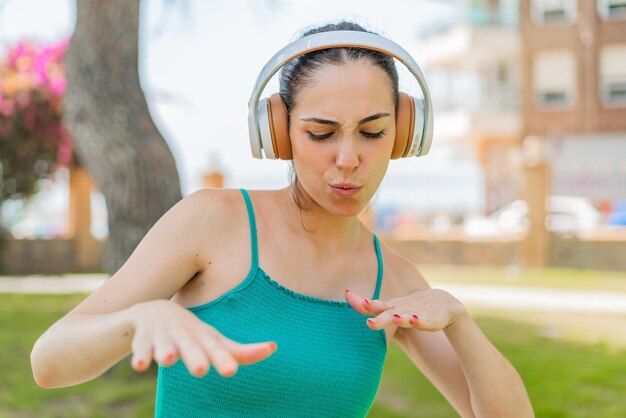 Foto mujer bonita joven al aire libre escuchando música y bailando