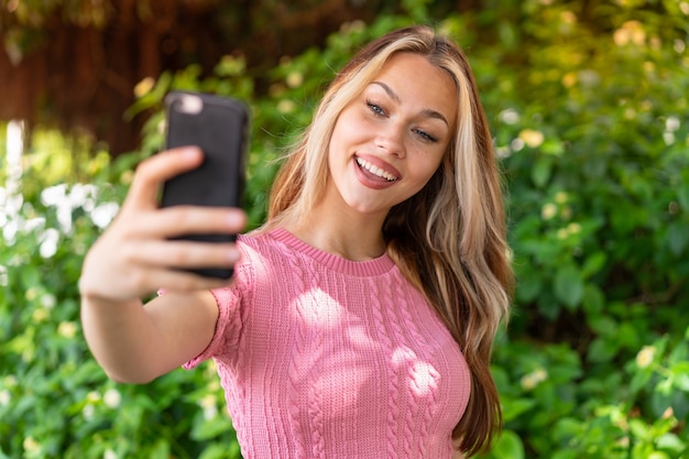 Mujer bonita joven al aire libre haciendo un selfie con teléfono móvil