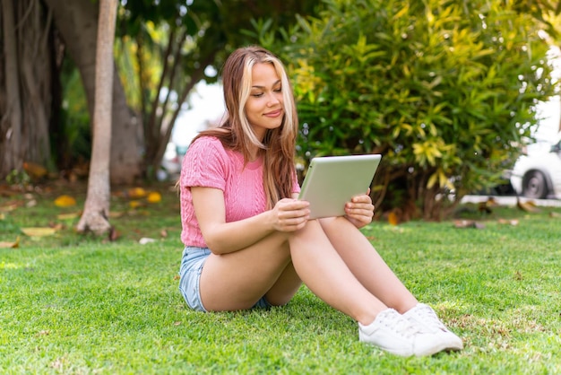 Mujer bonita joven al aire libre sosteniendo una tableta