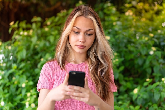 Mujer bonita joven al aire libre mediante teléfono móvil