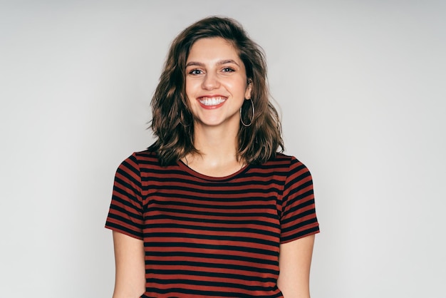 Mujer bonita joven alegre con ropa informal que muestra una sonrisa en el estudio