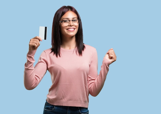 Foto mujer bonita joven alegre y sonriente, muy emocionada sosteniendo la nueva tarjeta bancaria