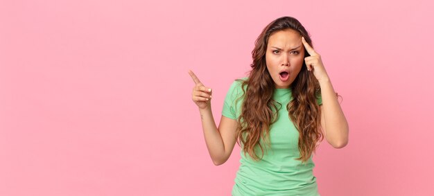 Mujer bonita joven y apuntando al espacio de la copia