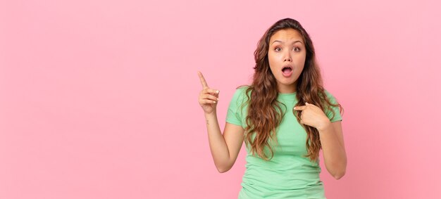 Mujer bonita joven y apuntando al espacio de la copia