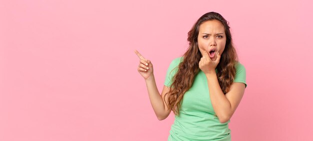 Mujer bonita joven y apuntando al espacio de la copia