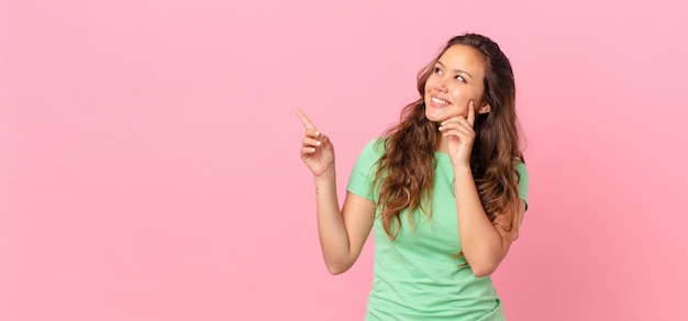 Mujer bonita joven y apuntando al espacio de la copia