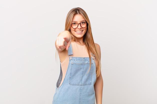 Mujer bonita joven apuntando al frente eligiéndote