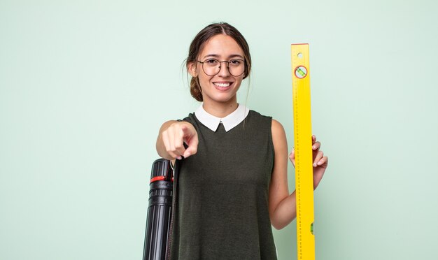 Mujer bonita joven apuntando a la cámara eligiéndote. concepto de arquitectura