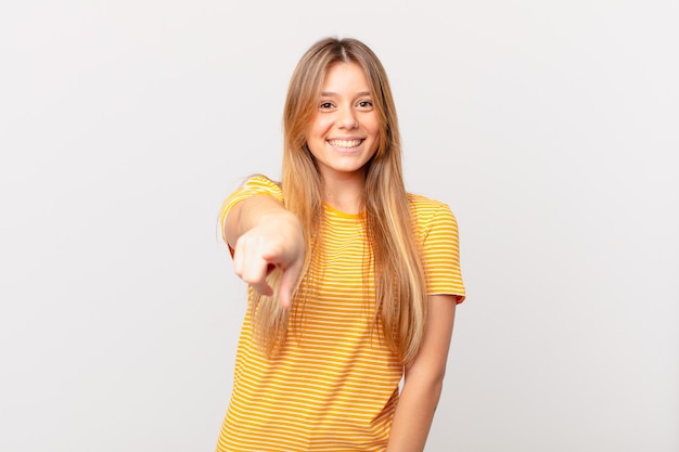 Mujer bonita joven apuntando a la cámara eligiéndote