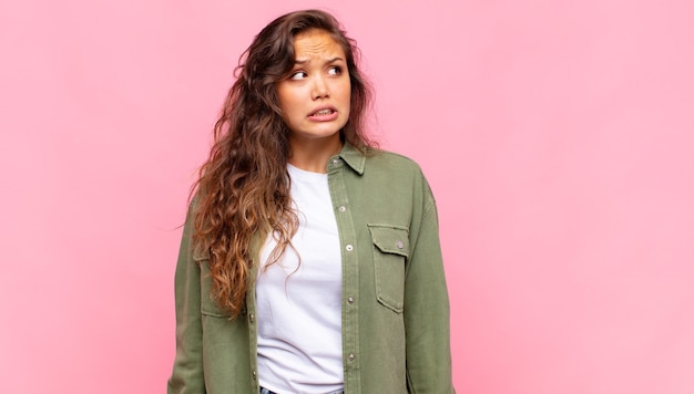 Mujer bonita joven asustada sobre fondo rosa