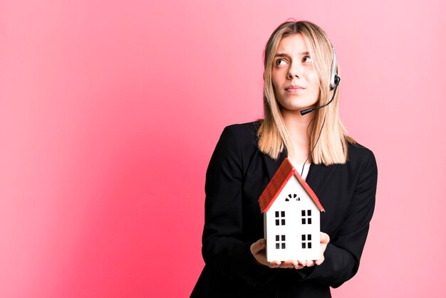 Mujer bonita joven con auriculares y un concepto de bienes raíces modelo de casa