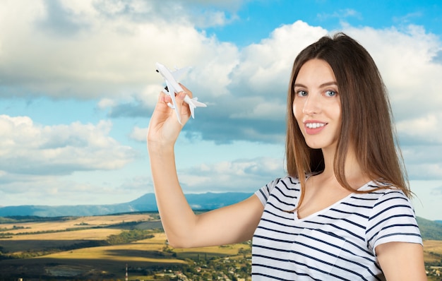 Mujer bonita joven con un avión de juguete de madera. Transporte o concepto de viaje