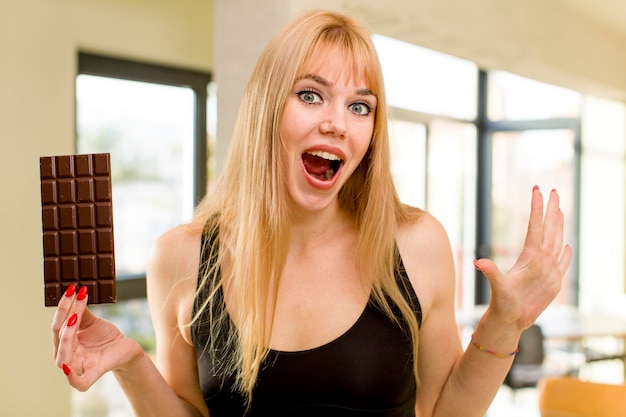 Mujer bonita joven con una barra de chocolate en el interior de su casa