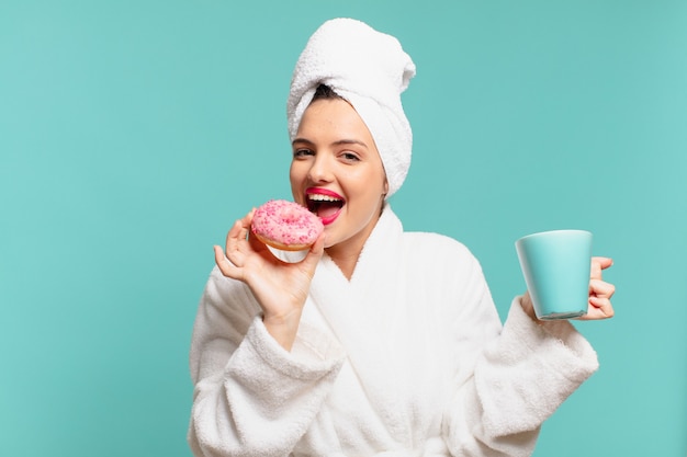 Mujer bonita joven en bata de baño con expresión feliz y desayunando