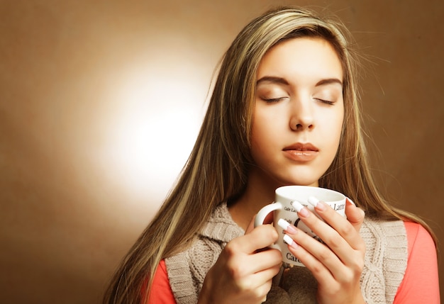 Mujer bonita joven bebiendo café sobre fondo beige