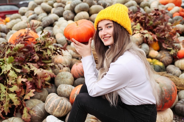 Mujer bonita joven con calabaza de halloween naranja