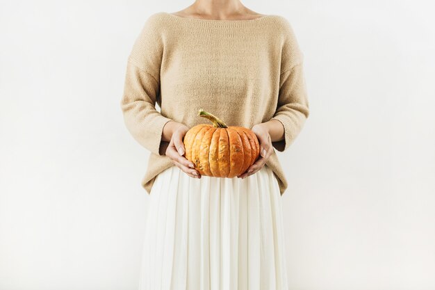 Mujer bonita joven con calabaza de halloween sobre superficie blanca