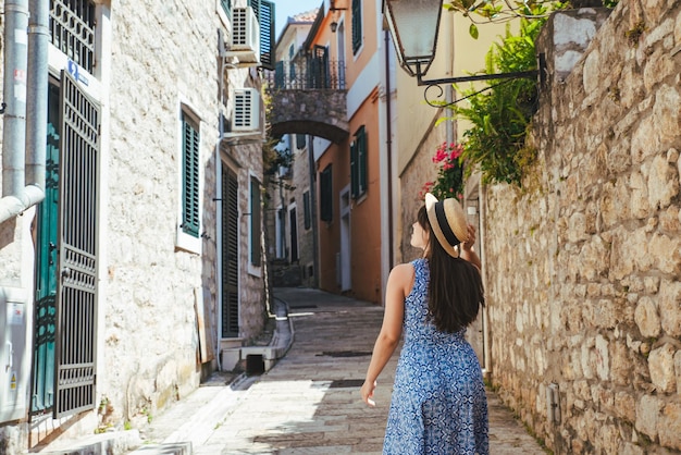 Mujer bonita joven caminando por las estrechas calles de la ciudad europea. vestido azul