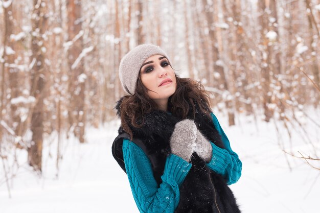 Mujer bonita joven caminando en el parque cubierto de nieve de invierno en día soleado