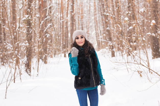 Mujer bonita joven caminando en el parque cubierto de nieve de invierno en día soleado