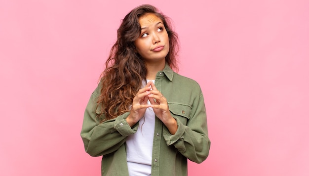 Foto mujer bonita joven con camisa abierta de mezclilla verde posando en la pared rosa