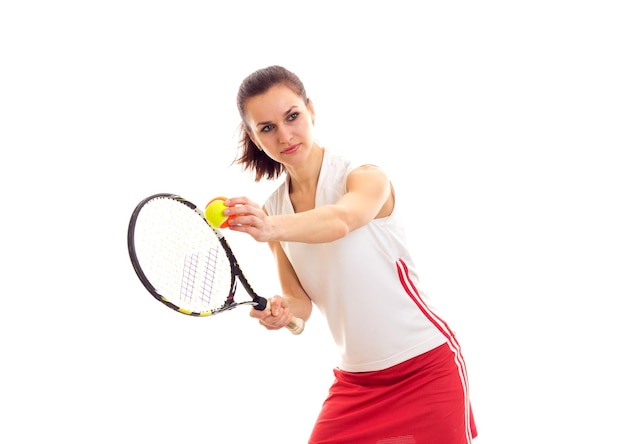 Mujer bonita joven en camisa deportiva blanca y falda roja con cola de caballo marrón con raqueta de tenis