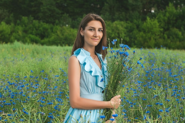 Mujer bonita joven entre el campo de hermosos acianos