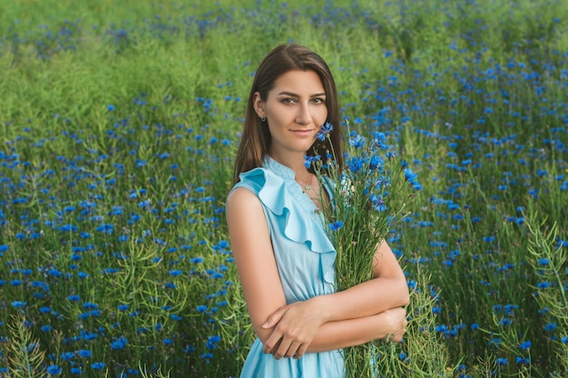 Mujer bonita joven entre el campo de hermosos acianos