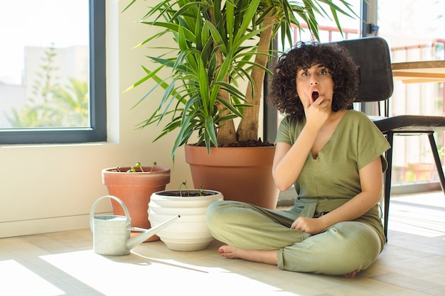 Mujer bonita joven en casa, con una regadera y plantas