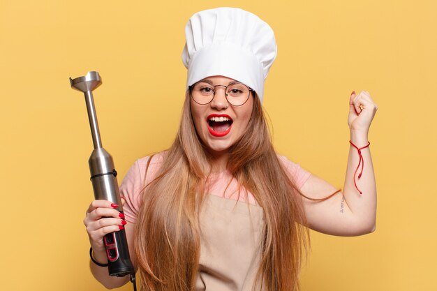 Mujer bonita joven. celebrando un triunfo como un concepto de chef ganador