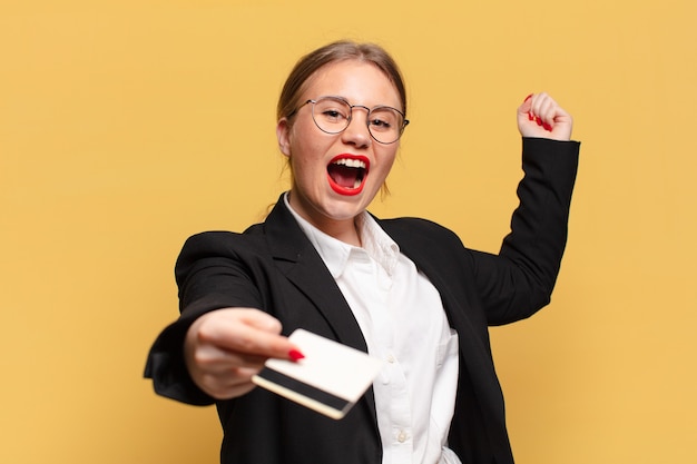 Mujer bonita joven. celebrando un triunfo como un concepto de tarjeta de crédito ganador