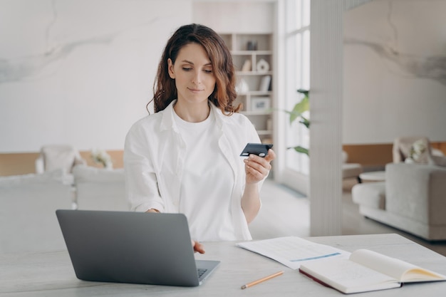 Mujer bonita joven va a comprar a través de internet Chica europea tiene tarjeta de crédito