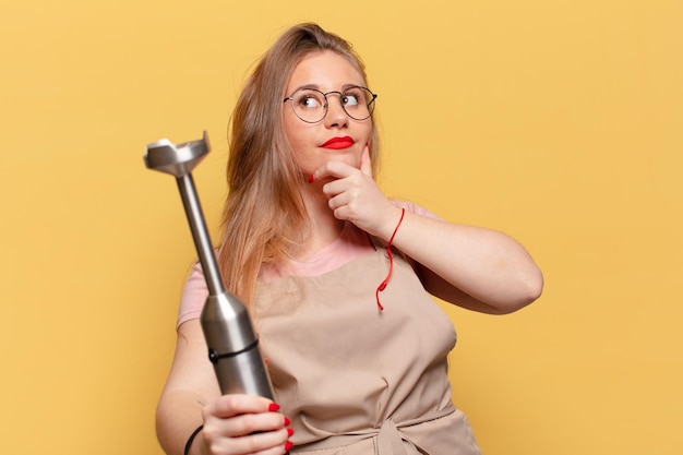 Mujer bonita joven. Concepto de licuadora de panadero de expresión de pensamiento o duda