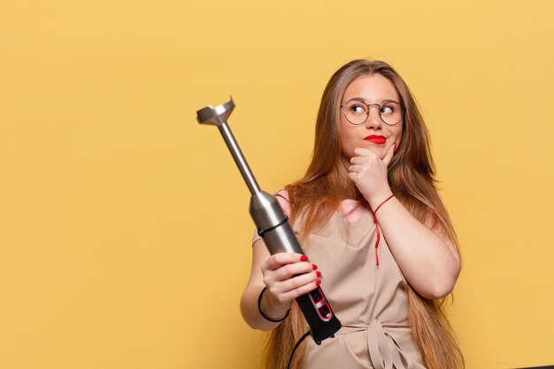 Mujer bonita joven. Concepto de licuadora de panadero de expresión de pensamiento o duda