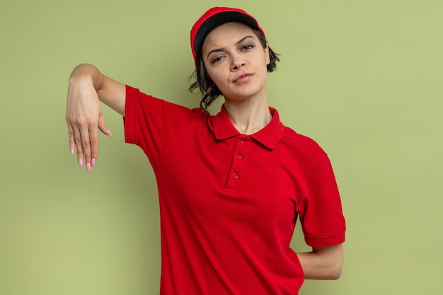 Mujer bonita joven confiada que mantiene la mano abierta y que mira al frente