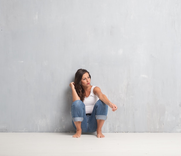 Foto mujer bonita joven contra fondo de la pared del cemento con un sp de la copia